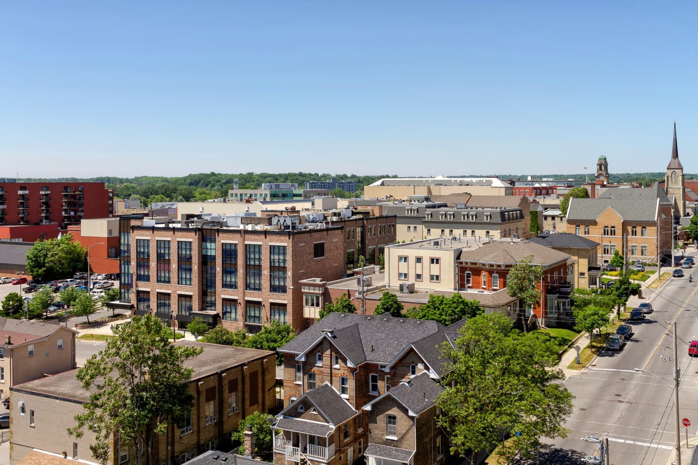 Cityscape of Brantford with historic buildings, tree-lined streets, and a church steeple in the background.