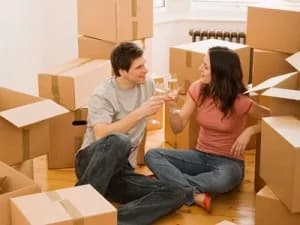 Couple celebrating with drinks while sitting among moving boxes