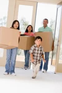 A family entering a new home with moving boxes, with a young boy happily leading the way