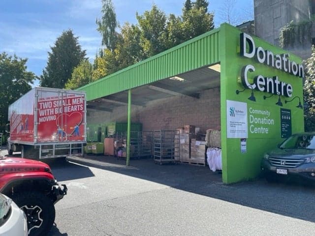 Two Small Men with Big Hearts Moving truck parked at a donation centre.
