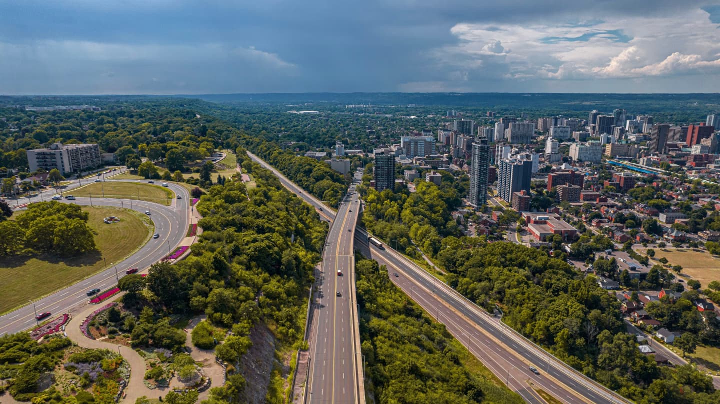 Aerial view of Hamilton, Ontario, showing the city's skyline, highways, and surrounding greenery.