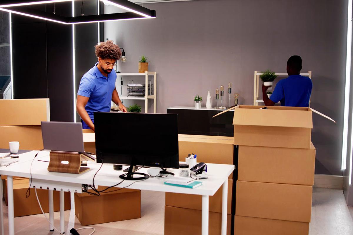 Movers packing boxes in an office setting.