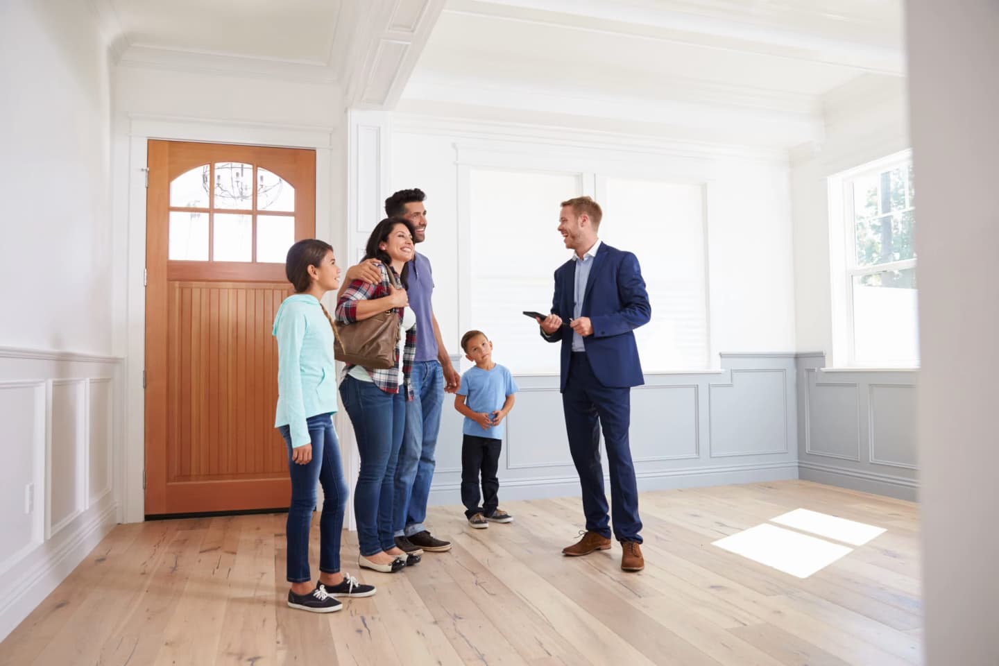 Real estate agent showing an empty house to a family with children