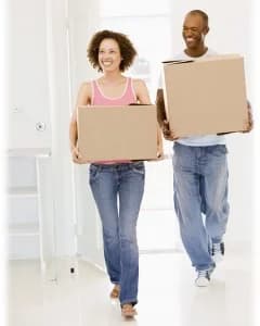 Smiling couple carrying moving boxes into their new home