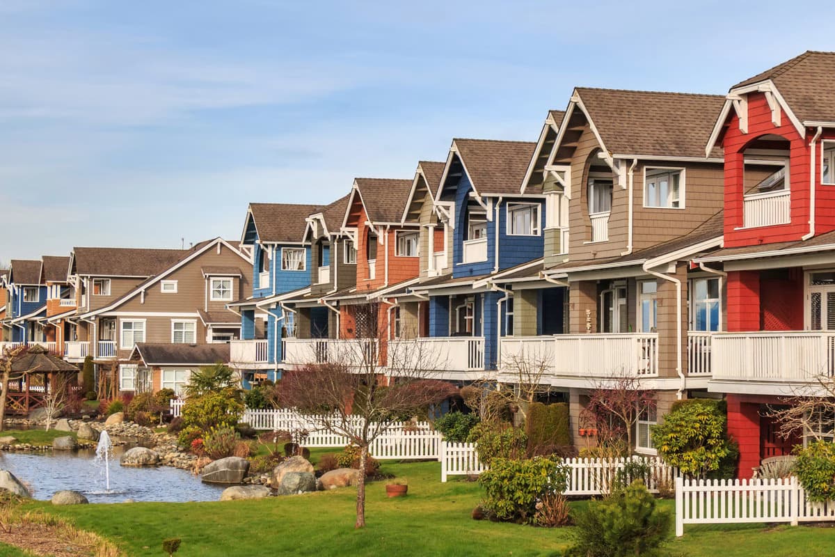 Colourful row of townhouses with white picket fences and landscaped gardens in Richmond, British Columbia.