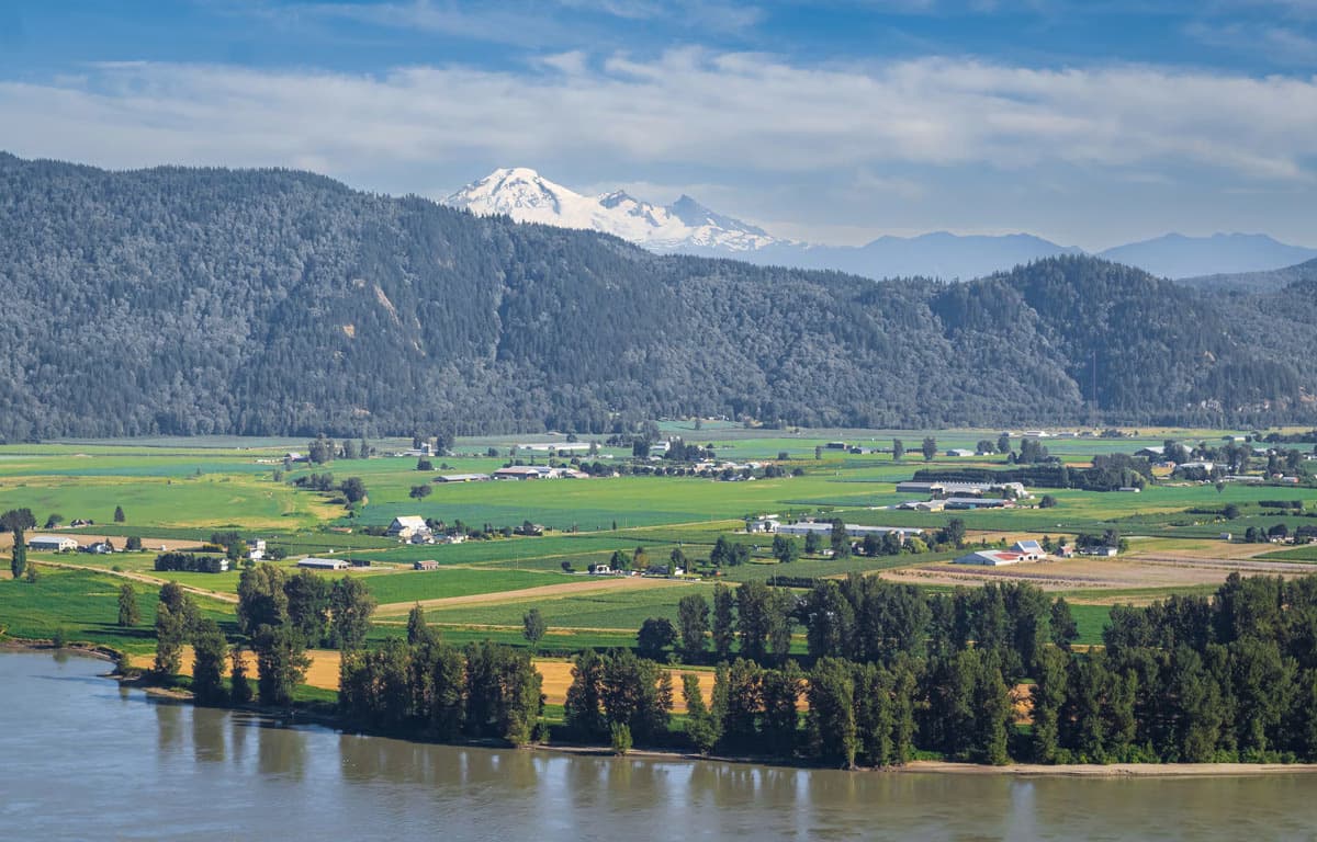 View of Abbotsford's green farmlands, Fraser River, and snow-capped mountains in the background.