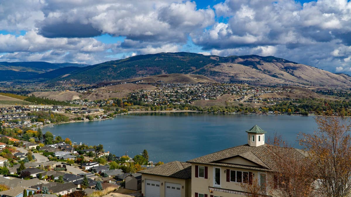 Aerial view of Vernon, British Columbia, with houses overlooking a lake and mountains in the background.