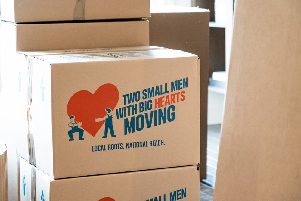 Moving box with Two Small Men with Big Hearts logo and slogan