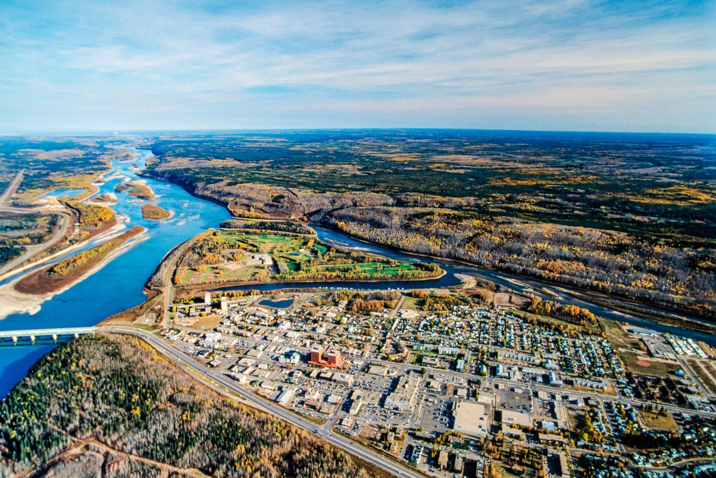 Aerial view of Fort McMurray with a river winding through the landscape and surrounding forested areas.