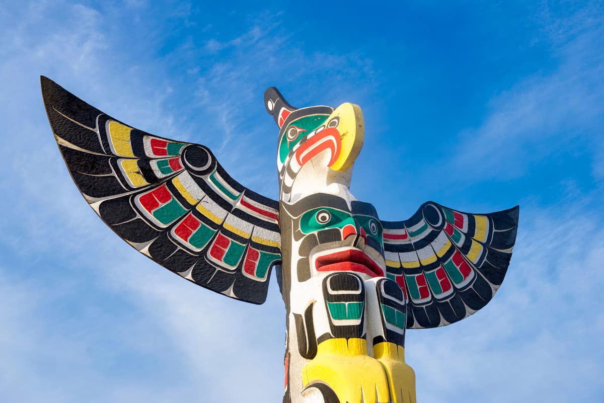 Colourful totem pole in Duncan against a bright blue sky.