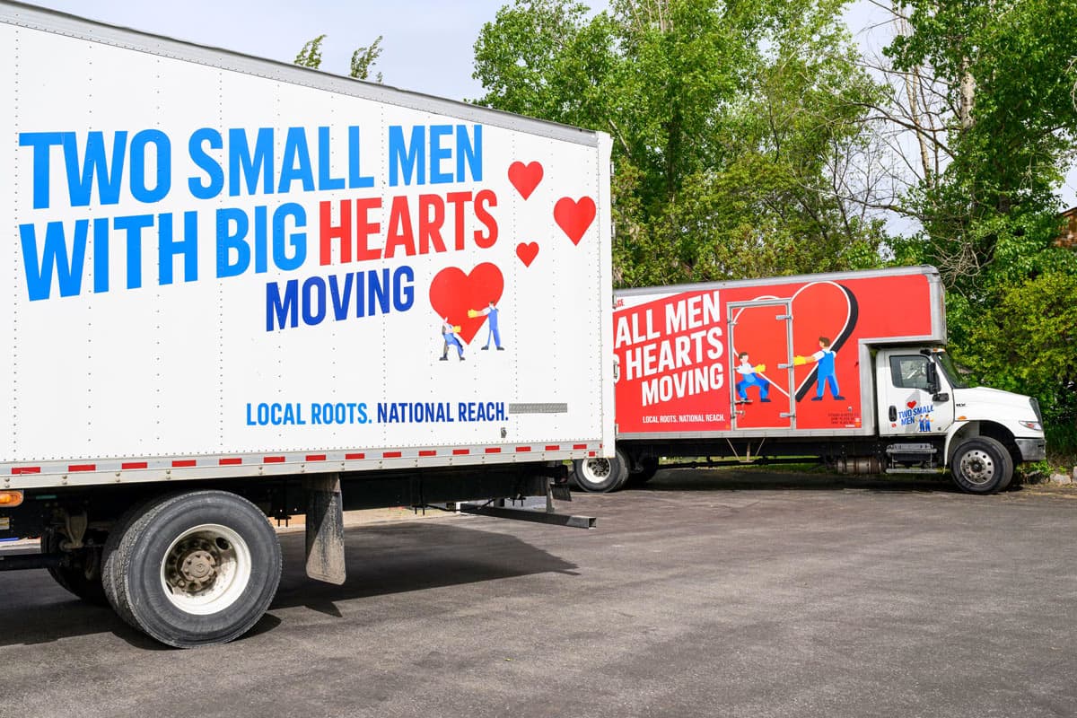 Two moving trucks from Two Small Men with Big Hearts Moving parked side by side.