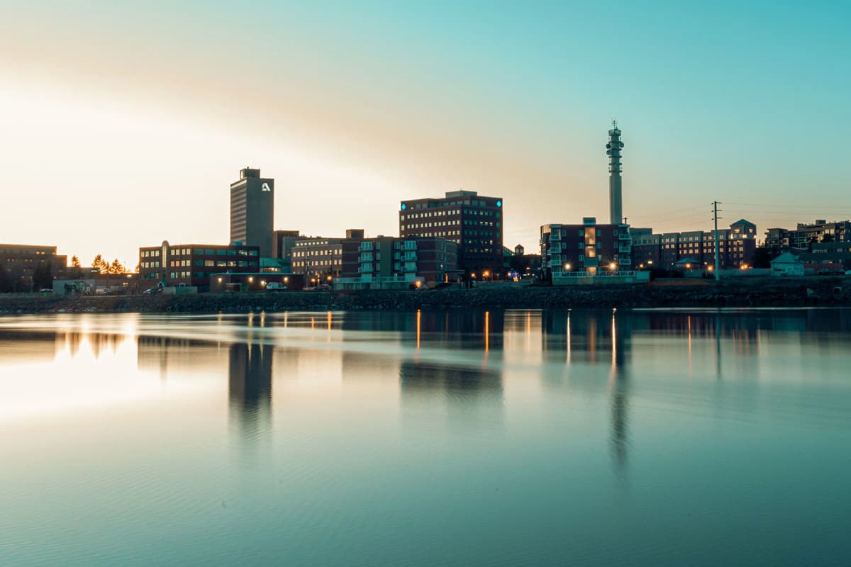 Cityscape of Moncton, New Brunswick, at sunset with reflections on the water.