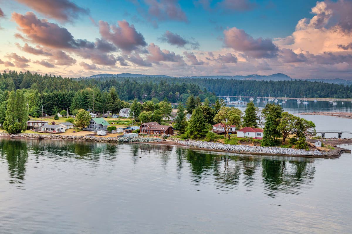 Coastal view of Nanaimo with houses along the shoreline, surrounded by trees and a calm body of water.